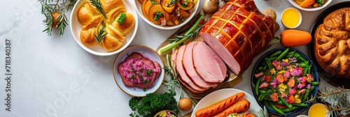 Classic Easter ham dinner. Top view table scene on a white background. Ham, eggs, hot cross buns, carrot, cake and vegetables. Panorama with copy space.