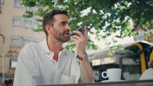 Stylish freelancer dictating voice message on phone street cafeteria close up © stockbusters