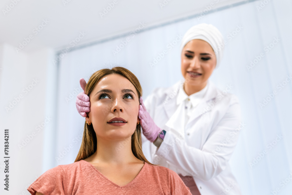 A doctor examines the patient before the aesthetic procedures. The patient looks at herself and tells her what she wants to change. A doctor examines the patient before the aesthetic procedures. The patient looks at herself and tells her what she wants to change.