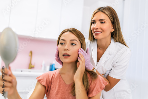 A doctor examines the patient before the aesthetic procedures. The patient looks at herself and tells her what she wants to change.