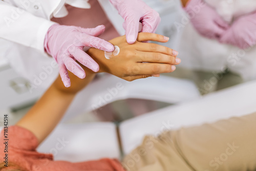 Doctor applying protective cream on patient s hands