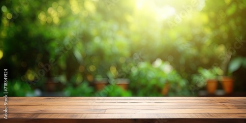 Wooden table with a blurred green backyard for an ad template. © Sona