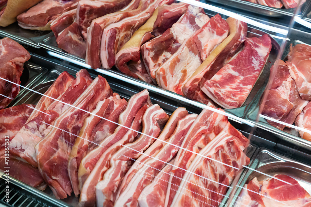 Assortment fresh raw pork cuts on display in butcher shop..