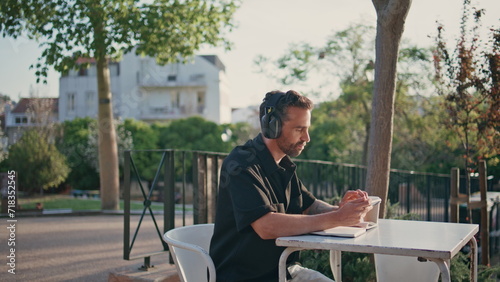 Inspired man enjoying music at wireless earphones sitting city street close up