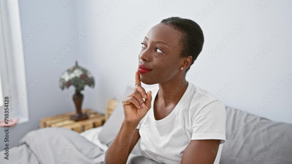 Thoughtful african american woman lying in comfort of bedroom, finger on chin in deep thought, concentrated doubt has her wondering and looking up Thoughtful african american woman lying in comfort of bedroom, finger on chin in deep thought, concentrated doubt has her wondering and looking up