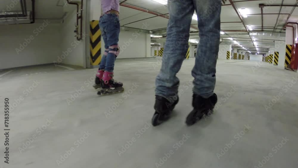 Happy girl and boy roller skate in underground parking, back view Happy girl and boy roller skate in underground parking, back view