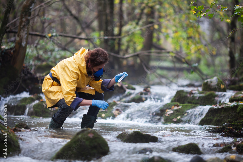 Adult Female Biologist in Yellow Raincoat Examining Water on Field for Possible Chemical Contamination Adult Female Biologist in Yellow Raincoat Examining Water on Field for Possible Chemical Contamination