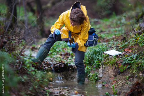 Mid Adult Biologist Collecting Samples of Water for Further Examination from a Water Stream in Countryside