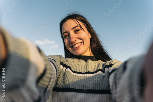 Joyful twentysomething Woman Capturing Selfie Moment at Urban Skate Park. Smiling young girl taking a selfie at a skate park, capturing urban life. photo