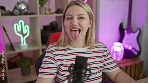 Blonde bombshell gamer gal, jubilantly sticking her tongue out, radiating crazy joy while streaming! young woman's hilarious facial expression lights up the fun night in a home gaming room.