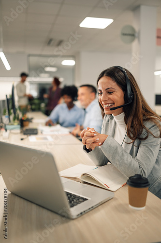 Smiling caucasian woman working in a call center and using a laptop and headset