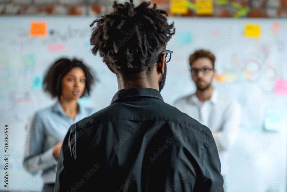 Obraz premium person standing in front of a whiteboard, brainstorming with a group of colleagues