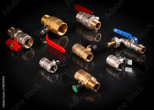 A set of metal and copper water pipe parts, a water wrench and pipe elbows, blue and red colors, black background, different shapes and different sizes