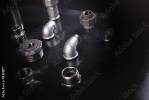 A set of metal and copper water pipe parts, a water wrench and pipe elbows, blue and red colors, black background, different shapes and different sizes