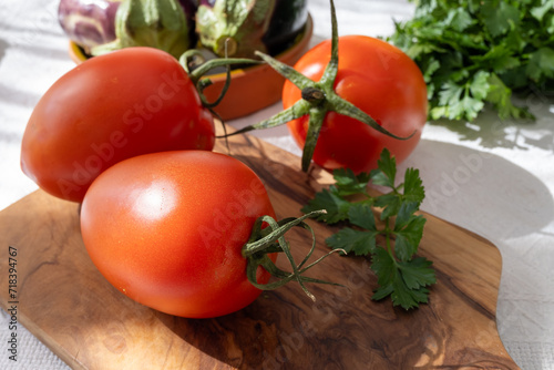 Ripe red Roma tomatoes in bowl with fresh herbs photo