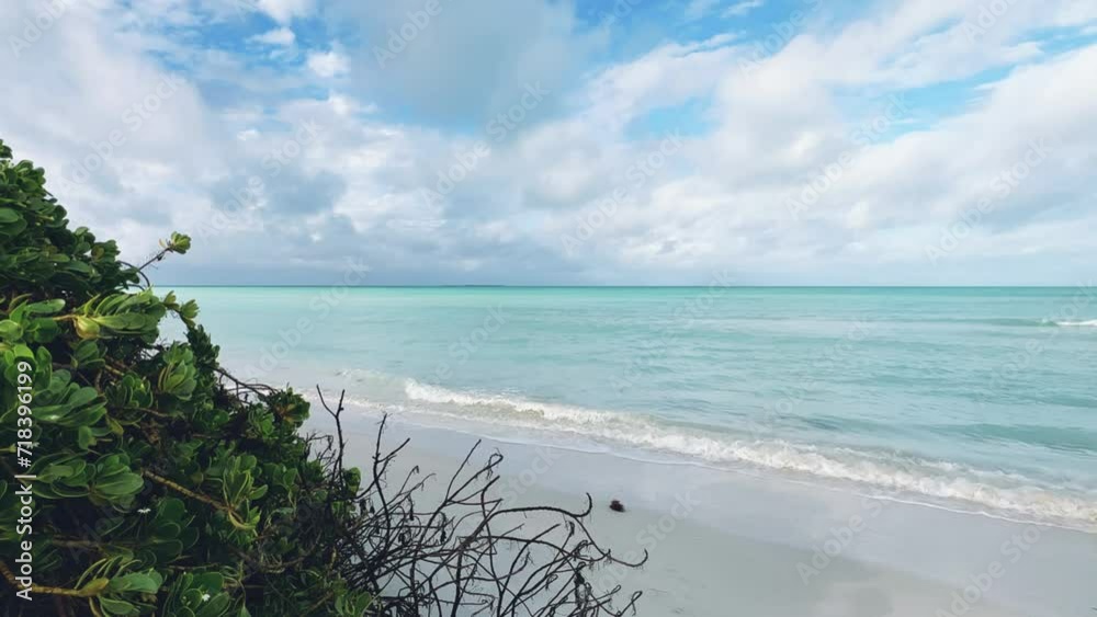 Beautiful Cuban beach in Varadero, Cuba, ocean waters against a background of green bushes on a cloudy day when the sun breaks through the clouds. A beach with snow-white sand. Turquoise waves. 4K Beautiful Cuban beach in Varadero, Cuba, ocean waters against a background of green bushes on a cloudy day when the sun breaks through the clouds. A beach with snow-white sand. Turquoise waves. 4K