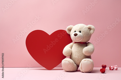Teddy bear alongside a red heart on a pink background.