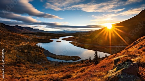  the sun is setting over a small lake in the middle of a grassy area with a mountain range in the background.