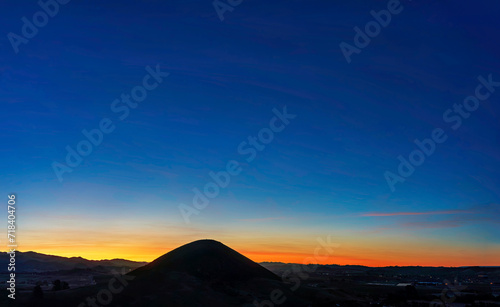 Sunset with silhouetted mountain, horizon at sunrise,