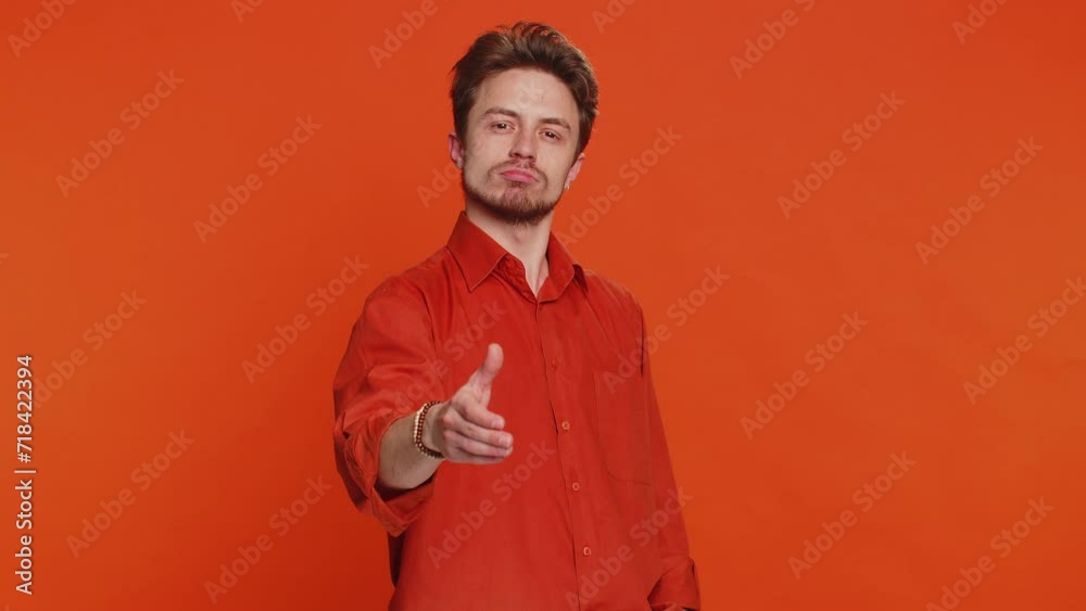 Friendly Caucasian man outstretching hand to camera offering handshake, greeting with kind smile invitation welcoming showing solidarity, trust concept. Young guy isolated on orange background indoors Friendly Caucasian man outstretching hand to camera offering handshake, greeting with kind smile invitation welcoming showing solidarity, trust concept. Young guy isolated on orange background indoors