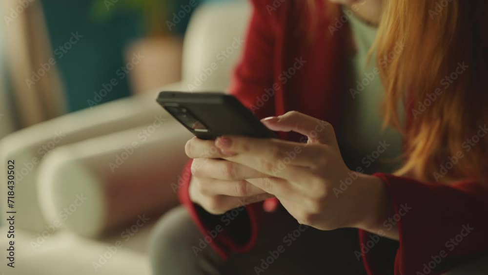 Young cute woman watching funny videos on her smart mobile. She is sitting on the sofa at home Young cute woman watching funny videos on her smart mobile. She is sitting on the sofa at home