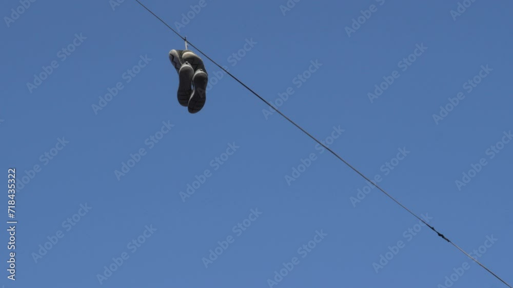Sneakers hung over a telephone line against a clear blue sky Sneakers hung over a telephone line against a clear blue sky