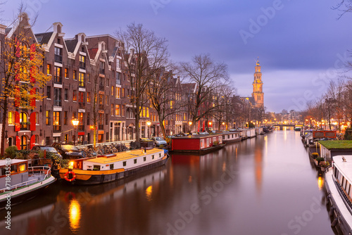 Night city view of Amsterdam canal Prinsengracht with houseboats and Westerkerk church, Holland, Netherlands. © Kavalenkava