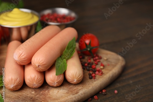 Delicious boiled sausages, basil and peppercorns on wooden table, closeup