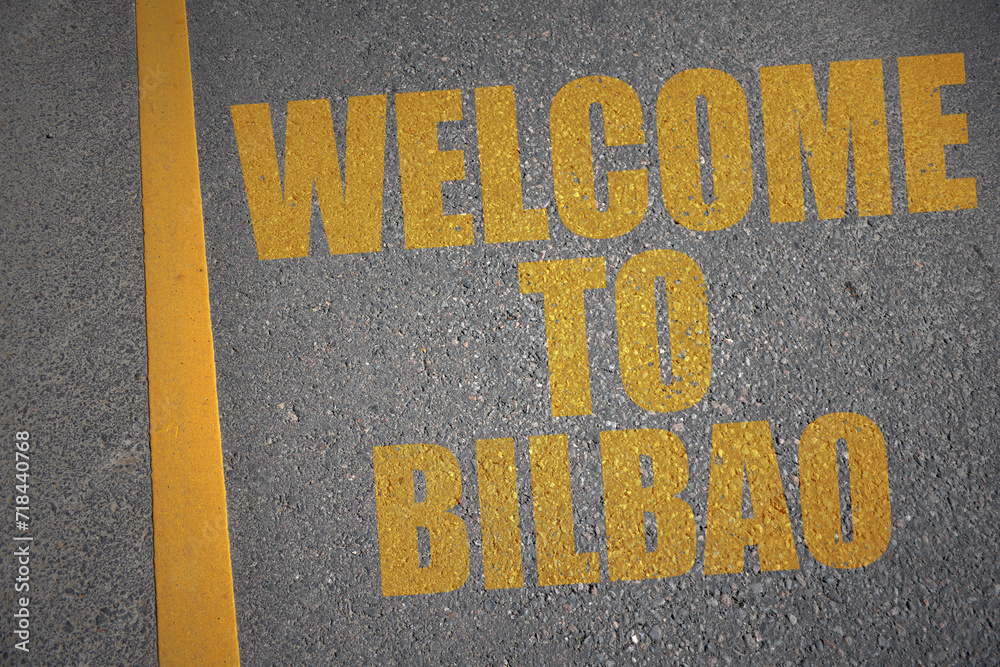 asphalt road with text welcome to Bilbao near yellow line.