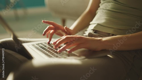 Cropped view of caucasian young woman sitting on the floor beside sofa in living room, working and typing on laptop photo