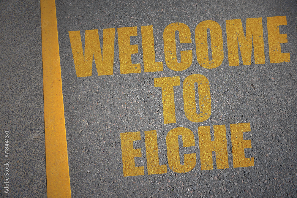 asphalt road with text welcome to Elche near yellow line.