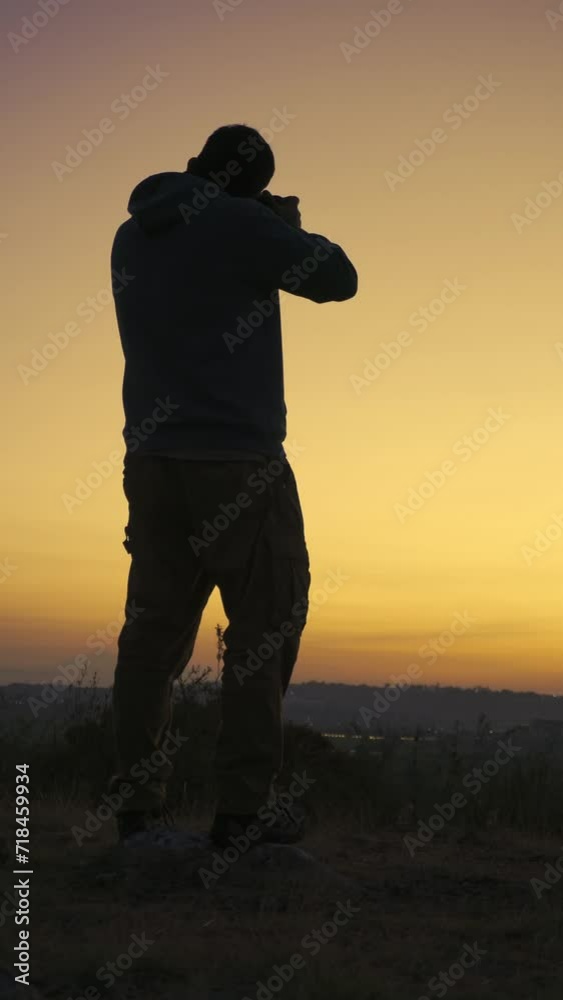 Silhouette of a young adventurer at dawn, equipped with backpack and camera, immortalizes the grandeur of the mountains. Silhouette of a young adventurer at dawn, equipped with backpack and camera, immortalizes the grandeur of the mountains.