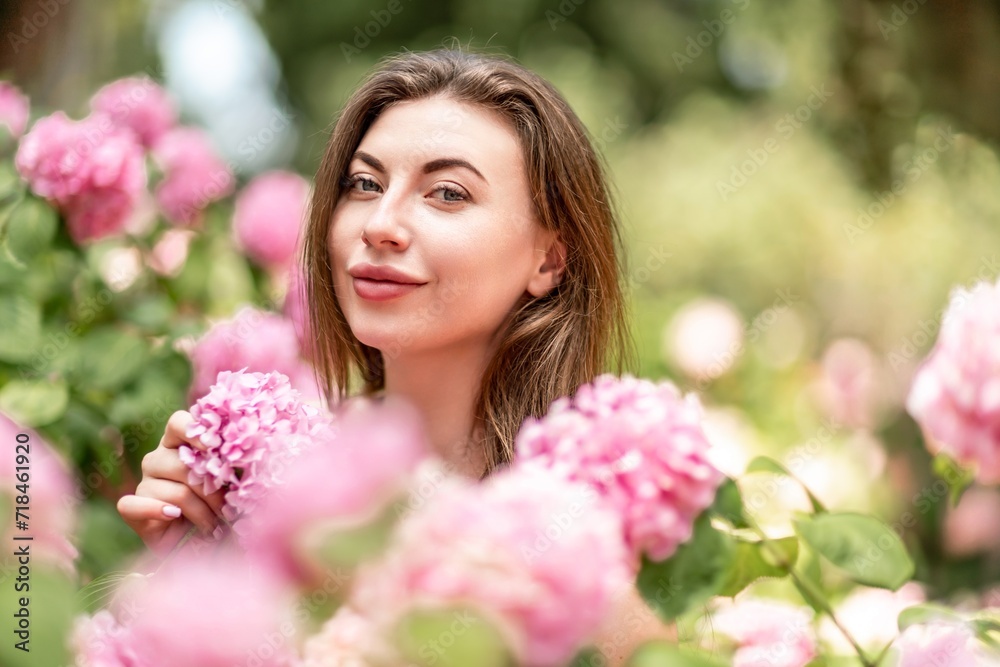 Hydrangeas Happy woman in pink dress amid hydrangeas. Large pink hydrangea caps surround woman. Sunny outdoor setting. Showcasing happy woman amid hydrangea bloom. Hydrangeas Happy woman in pink dress amid hydrangeas. Large pink hydrangea caps surround woman. Sunny outdoor setting. Showcasing happy woman amid hydrangea bloom.