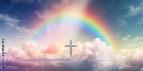 A religious cross illuminated by sunlight under a colorful rainbow amidst fluffy clouds in the sky.
