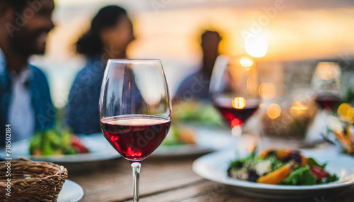 Radiant sunset dinner, blurred happy family, focus on a gleaming wine glass symbolizing warmth, togetherness, and shared moments