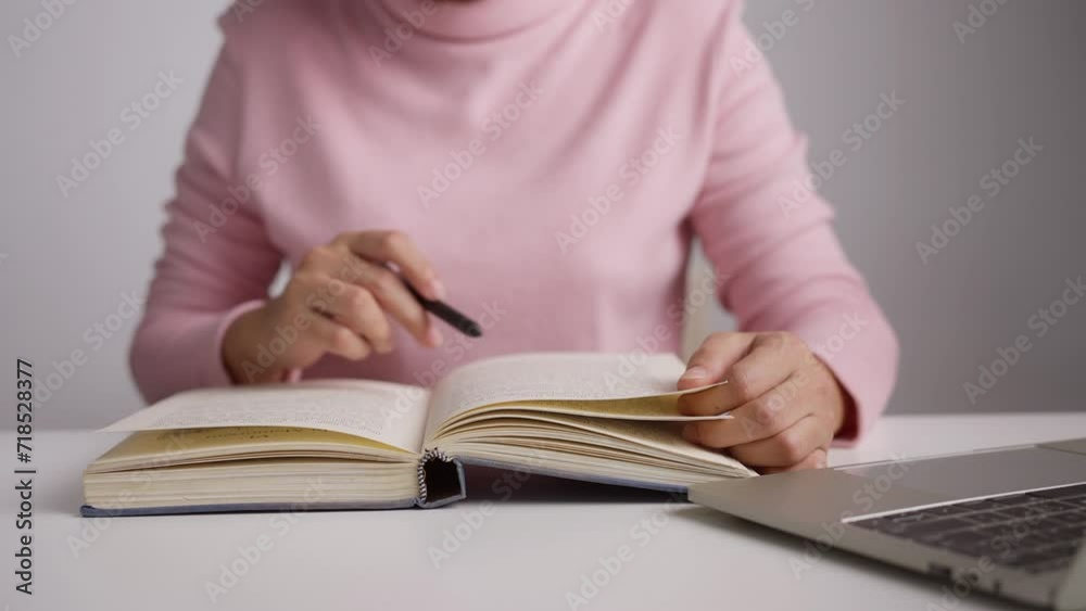 Close-up of female hands holding pen and turning page book. Woman reading book. Close-up of female hands holding pen and turning page book. Woman reading book.