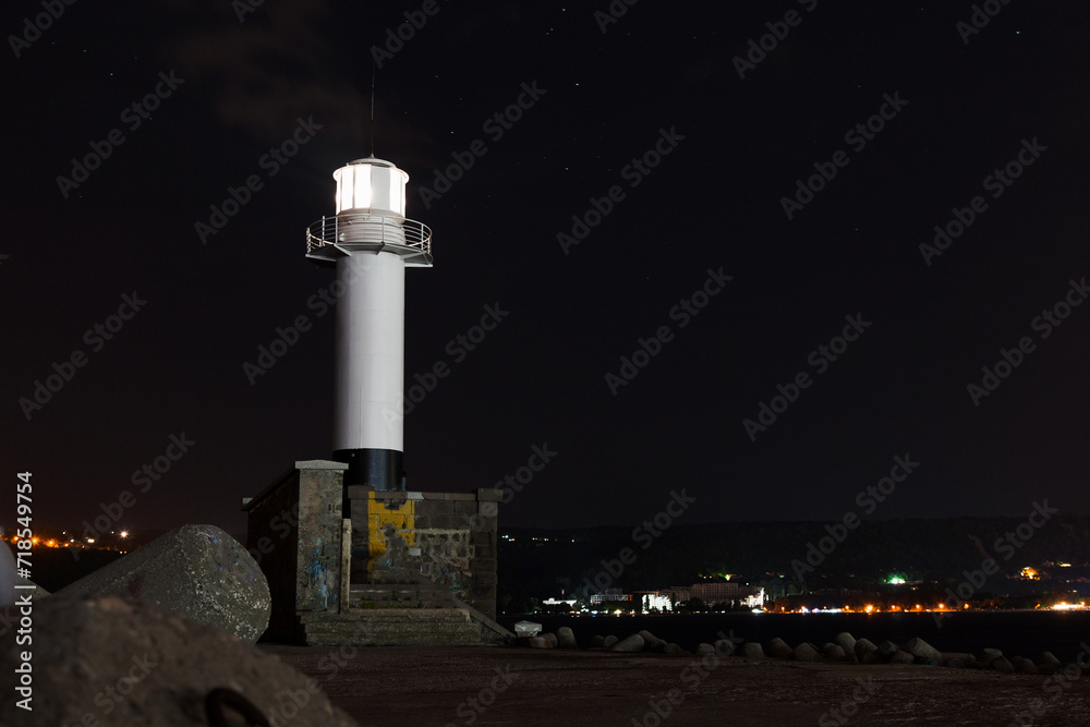 White lighthouse tower with glowing light. Night photo taken at Port of Varna