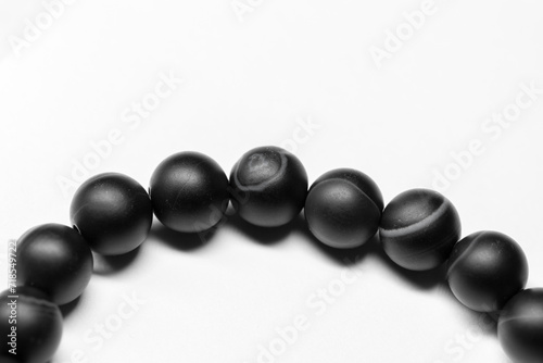 Bracelet made of round black agate beads lays on white background, close-up