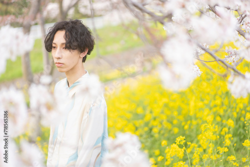 外を歩く若い男性/花が咲いている
