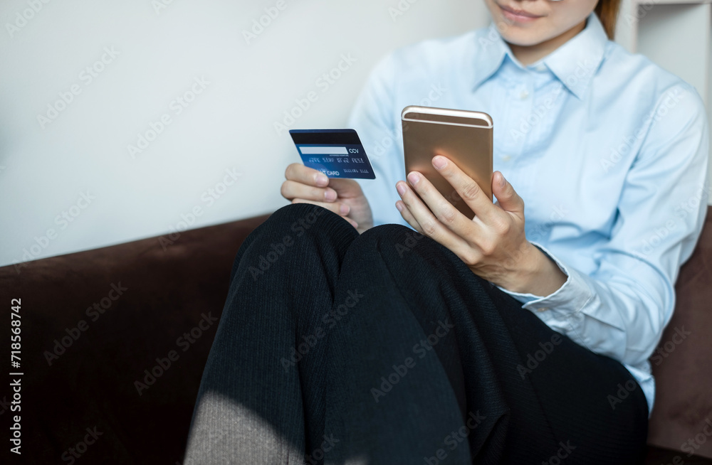 Asian girl shopping online holding credit and using smartphone enter their card number in the mobile phone app to purchase and payment in internet store