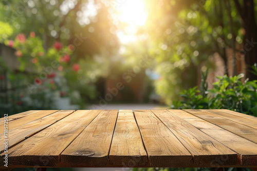  A wooden table with no objects on it and a blurred outdoor garden background. The wooden table provides space for text and can be used for marketing promotions