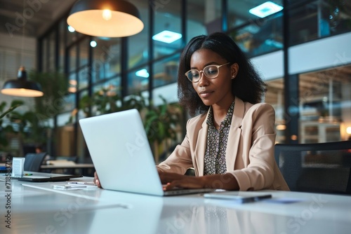 Busy professional business woman employee working looking at computer typing in office. Young African American female company finance manager executive using laptop sitting at desk. Generative AI