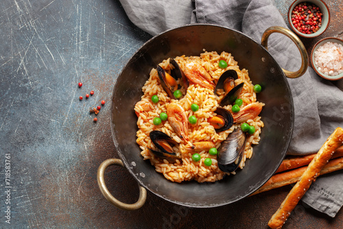 Traditional spanish seafood paella with rice, mussels, shrimps in a pan on concrete background. Top view. Flat lay