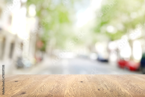 木目のある木製のテーブル越しに見えるボケた背景、奥行きのある背景、街の背景画像