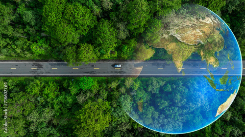 Aerial top view of green electric vehicle car driving over straight forest road, EV car electric vihicle car on forest road with globe green energy and eco power produced from sustainable.