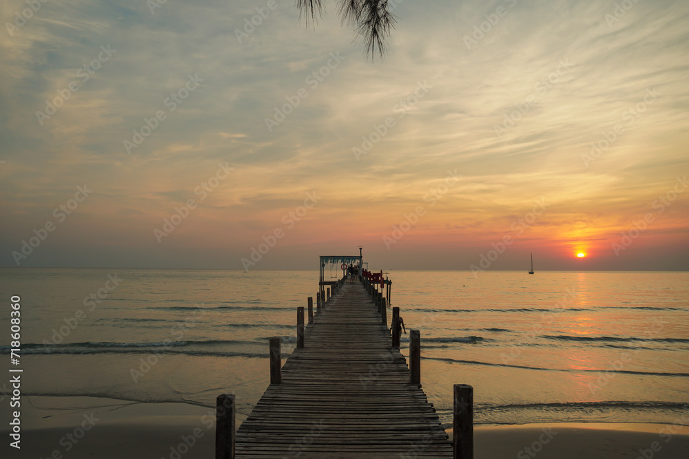 Fototapeta premium beautiful sunset at the wooden jetty at the beach. Wood bridge on the sea which has walk way for travel with beautiful sky and sunshine background.