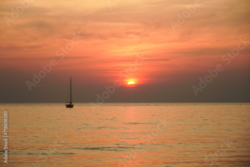 Sunset on the beach with long coastline, sun and dramatic sky. Tropical sea sunset. Sky background. Bright beautiful sunrise or sunset at sea.
