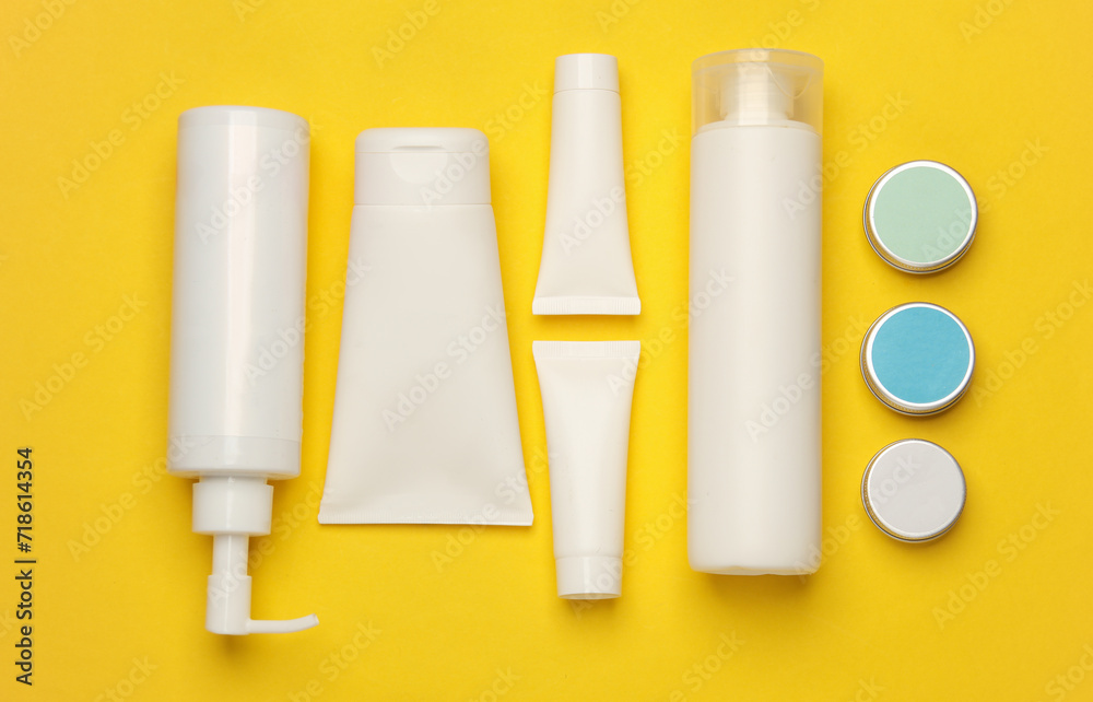 Tubes, bottles and jars of cosmetics on yellow background. Flat lay Tubes, bottles and jars of cosmetics on yellow background. Flat lay