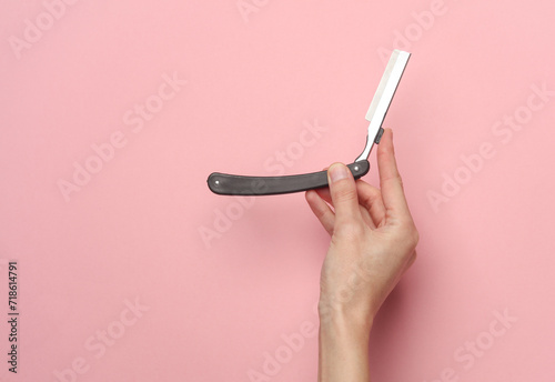 Cuadro en lienzo Hand holding a straight razor on a pink background