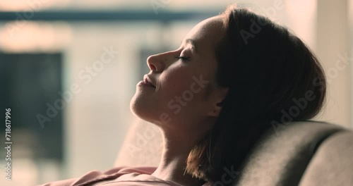 Close up side view, young woman put head on sofa take daytime nap in modern apartment or hotel room, enjoy silence, deep in dreaming, relieving exhaustion alone on weekend at home. Relax, stress-free photo